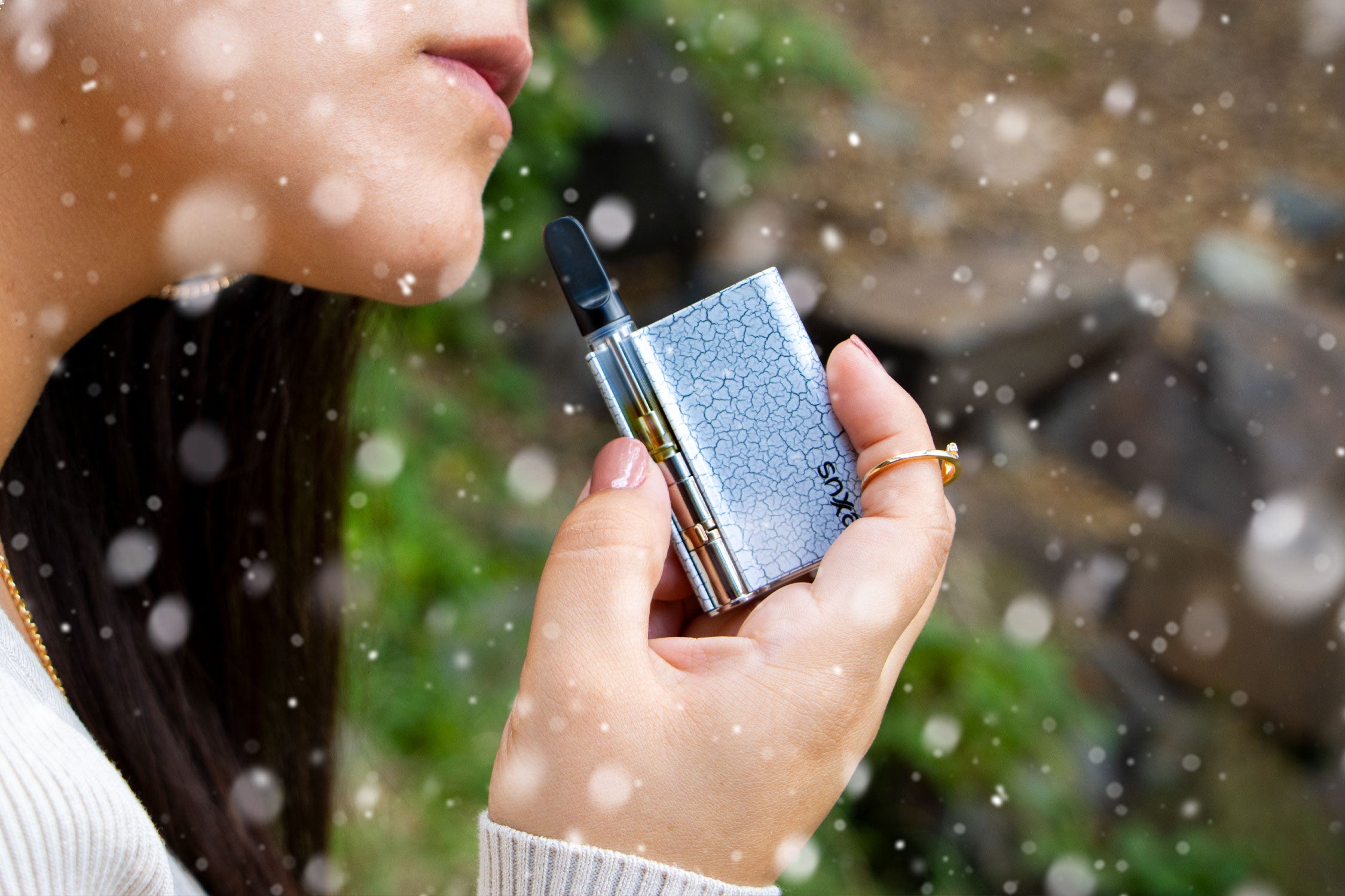 Woman holding Exxus Palm Pro Crackle in front of grassy trail with snow falling
